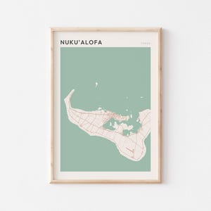May include: A framed print showing a map of Nuku'alofa, Tonga, in a minimalist style. The map is in beige and brown tones against a muted green backdrop. The text "NUKU'ALOFA" is at the top, with "TONGA" below it.