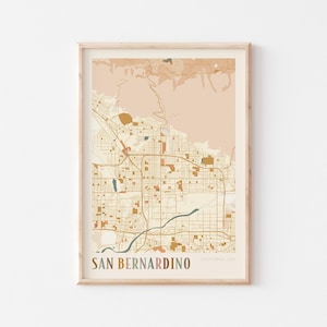 Puede incluir: Impresión enmarcada de un mapa de San Bernardino, California, en una paleta de colores neutros. El mapa presenta carreteras, edificios y elementos naturales. El texto "SAN BERNARDINO" está en la parte inferior de la impresión.