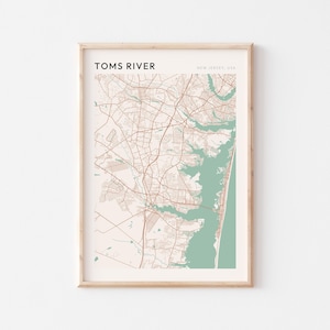 May include: A framed map print of Toms River, New Jersey, USA. The map shows the city's layout with roads and waterways in brown and green against a cream background. The text "TOMS RIVER" is at the top.