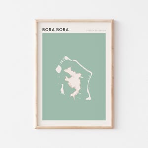 Könnte beinhalten: Ein gerahmter Kunstdruck mit einer minimalistischen Karte von Bora Bora in Französisch-Polynesien. Die Karte ist hellbeige auf einem gedämpften grünen Hintergrund. Die Wörter "BORA BORA" und "FRANZÖSISCH-POLYNESIEN" sind in Schwarz gedruckt.