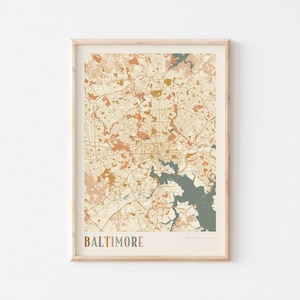 May include: A framed print of a map of Baltimore, Maryland, USA. The map shows the city's layout in beige, orange, and teal. The word "BALTIMORE" is printed at the bottom in a multi-coloured font.