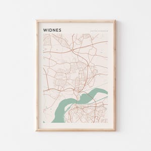 Puede incluir: Impresión enmarcada del mapa de Widnes, Reino Unido. El mapa presenta una red de carreteras y edificios marrones sobre un fondo beige claro. Un río de color turquesa fluye por el centro. La palabra "WIDNES" está impresa en la parte superior.