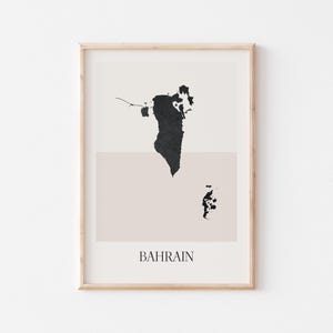May include: A framed art print featuring a minimalist map of Bahrain in black against a neutral background. The word "BAHRAIN" is printed in a simple font at the bottom of the print. The artwork is encased in a light-colored wooden frame.