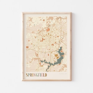 Puede incluir: Una impresión enmarcada de un mapa de Springfield, Illinois, en una paleta de colores neutros. El mapa presenta una cuadrícula detallada de calles, parques y un lago. La palabra "SPRINGFIELD" está impresa en marrón en la parte inferior.