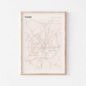 Puede incluir: Una impresión enmarcada de un mapa de York, Reino Unido. El mapa presenta la red de carreteras de la ciudad en tonos marrones y beige, con el nombre de la ciudad en la parte superior izquierda. Las palabras "United Kingdom" están en la parte superior derecha.