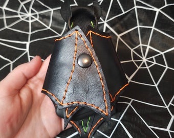 May include: Black leather bat-shaped keychain with orange stitching and a metal ring.