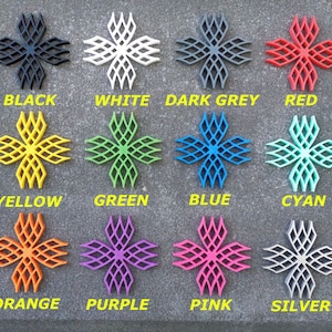 Puede incluir: Doce objetos con forma de estrella impresos en 3D en varios colores, incluyendo negro, blanco, gris oscuro, rojo, amarillo, verde, azul, cian, naranja, morado, rosa y plateado.