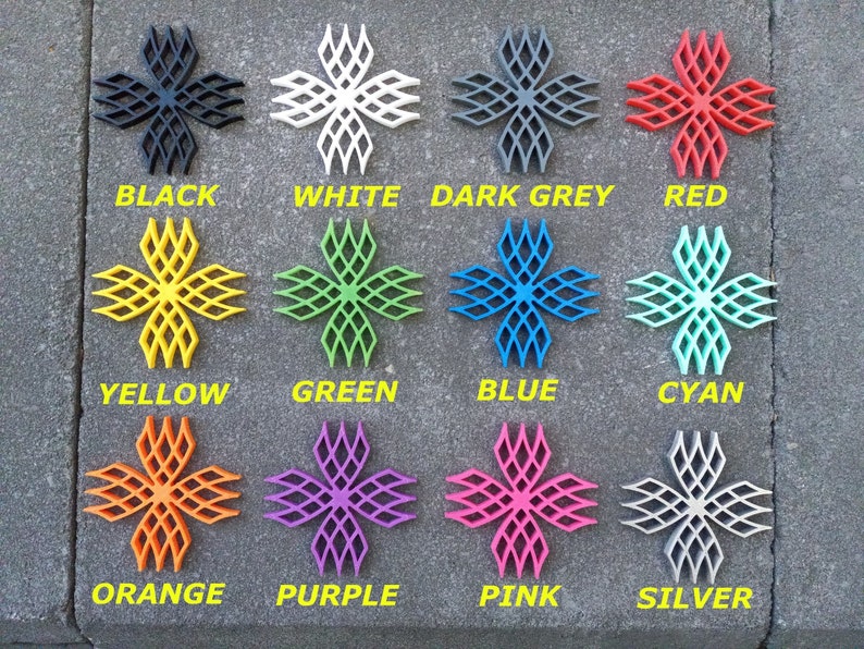 Puede incluir: Doce objetos con forma de estrella impresos en 3D en varios colores, incluyendo negro, blanco, gris oscuro, rojo, amarillo, verde, azul, cian, naranja, morado, rosa y plateado.
