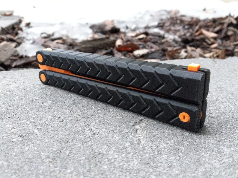 Puede incluir: Un cuchillo plegable de bolsillo negro y naranja con un mango texturizado. El cuchillo est&aacute; cerrado y tiene un seguro de seguridad.