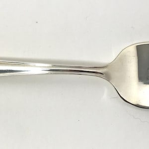 May include: A silver fork with a decorative handle. The fork has three tines and a smooth, polished finish.