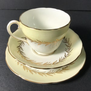 May include: A vintage teacup and saucer set with a yellow and gold floral design. The cup and saucer have a delicate, scalloped edge.
