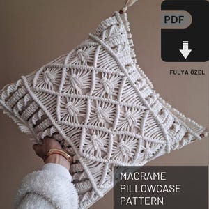 Könnte beinhalten: Ein weißes Makramee-Kissenbezug-Muster als PDF-Download. Das Muster hat ein geometrisches Design mit einer Diamantform.