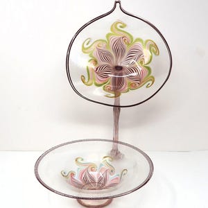 Può includere: Due ciotole di vetro trasparente con motivi floreali rosa e verdi. Le ciotole sono su uno sfondo bianco.