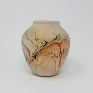 May include: A beige ceramic vase with a marbled design. The vase features swirls of brown, green, and black against a beige background. The vase has a rounded body and a narrow neck, suitable for home decor.