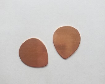 May include: Two copper guitar picks in the shape of a teardrop.