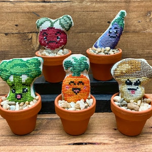 Puede incluir: Seis pequeñas plantas en maceta con caras bordadas lindas. Las plantas son un rábano rojo, un brócoli verde, una zanahoria naranja, una berenjena morada, un hongo marrón y un cactus verde.
