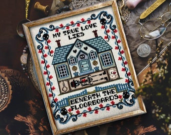Puede incluir: Bordado de punto de cruz en un marco de madera con una casa azul y blanca y el texto "My true love lies beneath the floorboards".