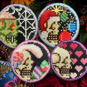 Puede incluir: Cinco adornos redondos bordados con un diseño de calavera. Cada adorno presenta un diseño diferente, incluyendo un tema navideño, un tema floral y un tema de corazón. Los adornos son todos en blanco y negro con acentos de colores.