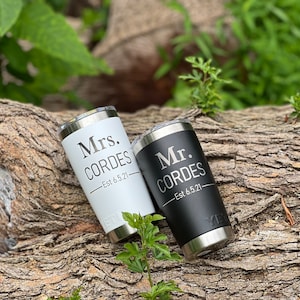 May include: Two stainless steel tumblers with black and white lids. The white tumbler has "Mrs. CORDES - Est 6.5.21" engraved on it. The black tumbler has "Mr. CORDES - Est 6.5.21" engraved on it.