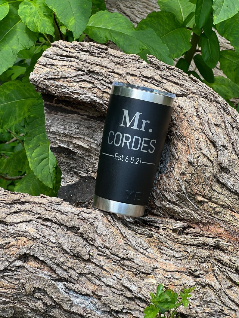 May include: Black stainless steel tumbler with a black lid and a silver inscription that reads "Mr. Cordes - Est 6.5.21".