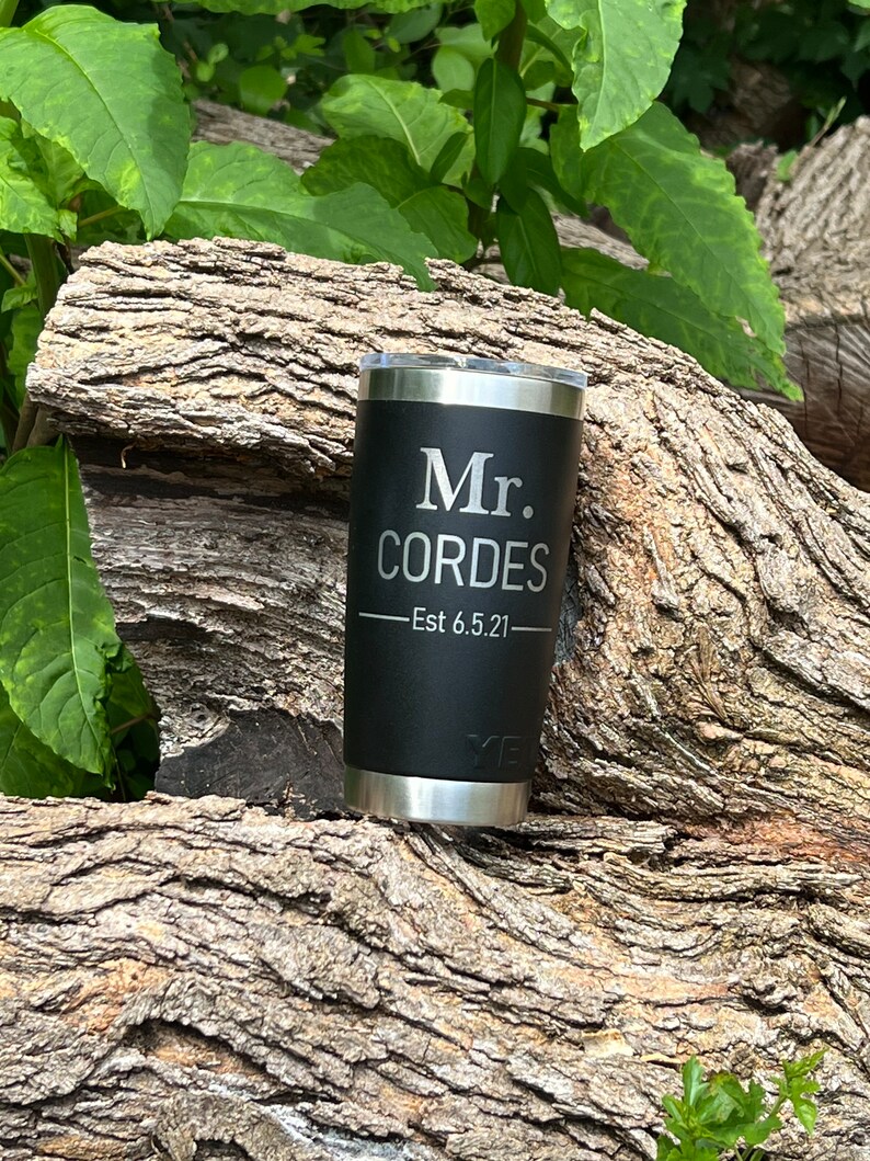 May include: Black stainless steel tumbler with a silver lid. The tumbler has the text "Mr. CORDES - Est 6.5.21" engraved on the side.