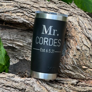 May include: Black stainless steel tumbler with a silver inscription that reads "Mr. Cordes - Est 6.5.21".