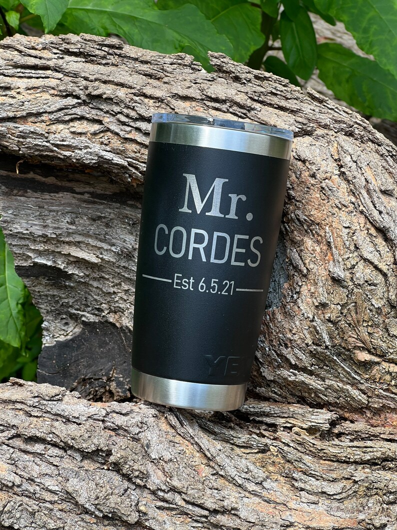 May include: Black stainless steel tumbler with a silver inscription that reads "Mr. Cordes - Est 6.5.21".