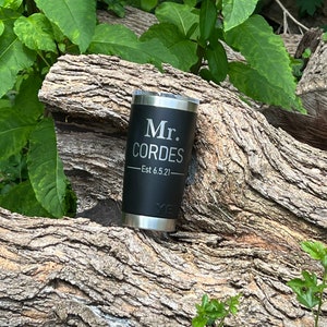 May include: Black stainless steel tumbler with a personalized inscription that reads "Mr. Cordes - Est 6.5.21".