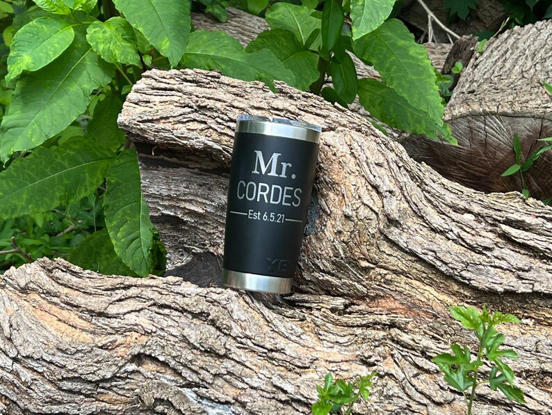 May include: Black stainless steel tumbler with a personalized inscription that reads "Mr. Cordes - Est 6.5.21".