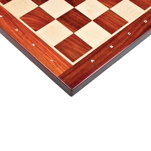 May include: A wooden chessboard with a dark reddish-brown border and alternating light and dark squares. The board's edge features white letter and number markings for game play.