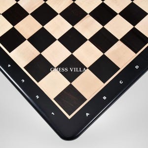 Puede incluir: Primer plano de un tablero de ajedrez con cuadrados negros y de madera clara alternados. El tablero tiene un borde negro con números y letras blancas. El texto "CHESS VILLA" es visible.