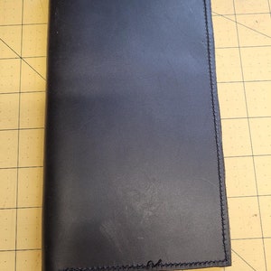 May include: A black leather notebook with stitched edges.