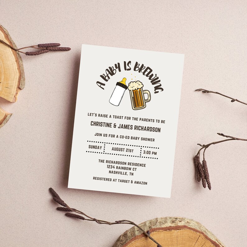 Op de afbeelding: Een uitnodiging voor een babyshower met de zin "A Baby is Brewing" in een speels lettertype. De uitnodiging bevat een babyfles en een bierpul-afbeelding. Details zijn de namen van de ouders, datum, tijd en locatie.