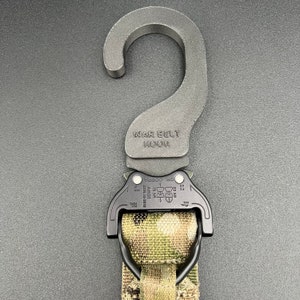 May include: A black tactical belt hook with a metal buckle and a camouflage webbing strap. The hook is labeled "WAR BELT HOOK" and "DR COBRA".