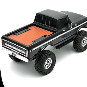 May include: Black Ford pickup truck with a wooden bed. The truck has large tires and a chrome bumper.