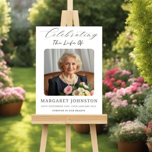 May include: A white easel with a sign that reads "Celebrating The Life Of" with a photo of a woman and the text "Margaret Johnston 06th September 1950 - 24th January 2025 Forever in Our Hearts".