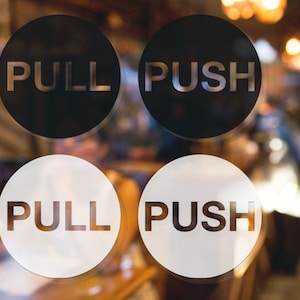 May include: Four round signs with black and white backgrounds. Two signs say "PULL" and two signs say "PUSH".