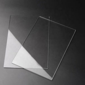 May include: Two clear acrylic sheets, one slightly larger than the other, are stacked on top of each other. The sheets are smooth and translucent, with a slight sheen.