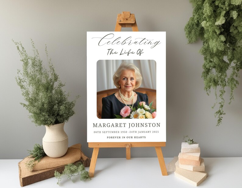 May include: A white memorial sign with a black border and a photo of a woman with a bouquet of flowers. The text reads "Celebrating The Life Of Margaret Johnston 06th September 1950 - 24th January 2025 Forever In Our Hearts."