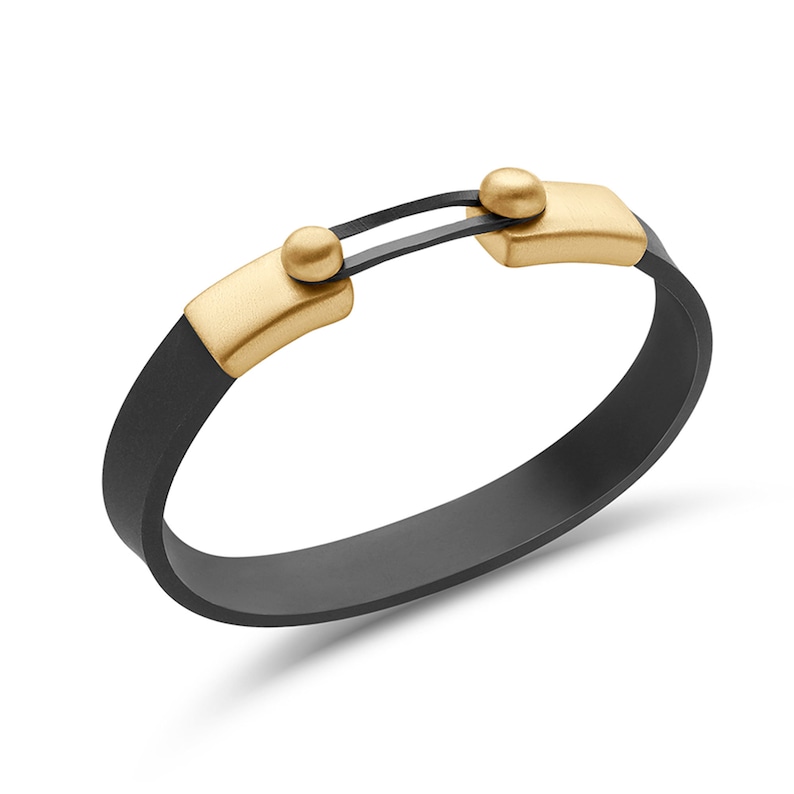 Puede incluir: Una pulsera de silicona negra con un cierre dorado y dos detalles dorados. La pulsera es ajustable y tiene un dise&ntilde;o moderno.