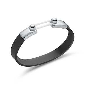 Könnte beinhalten: Ein schwarzes Silikonarmband mit einem silbernen Verschluss und einem weißen Gummiband.