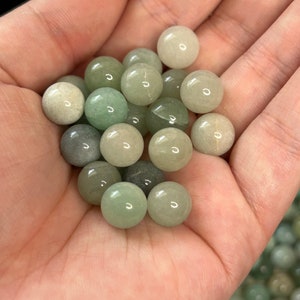 May include: A collection of smooth, green and white gemstone spheres. The spheres are various shades of green and white, and they are all about the size of a marble.