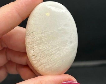 May include: White oval-shaped polished stone with a white and gold striated pattern.