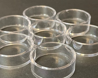 May include: A set of eight clear plastic napkin rings. The rings are stacked on top of each other.