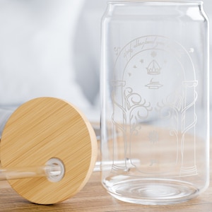 May include: A clear glass can with a bamboo lid and a straw. The can has an etched design of the entrance to the Shire from The Lord of the Rings.