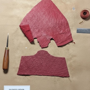 May include: Red ostrich leather panels for custom projects. The image shows two pieces of textured red leather, a leather punch, thread, and a ruler. The text on the label reads: DIY EXOTIC LEATHER - GENUINE RED OSTROICH SKIN - Panels for Custom - Premium Quality.