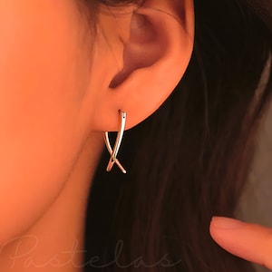May include: A pair of gold-toned hoop earrings with a criss-cross design.