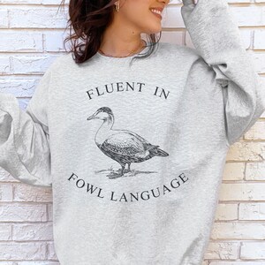 May include: A gray sweatshirt with a black graphic of a duck and the text "Fluent in Fowl Language".