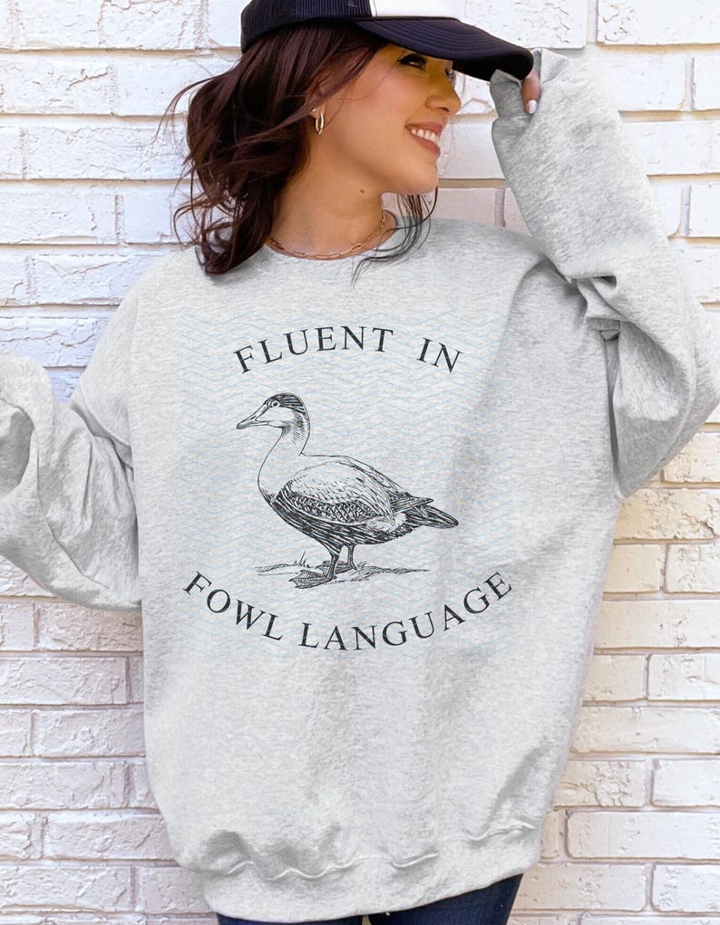 May include: A gray sweatshirt with a black graphic of a duck and the text "Fluent in Fowl Language".