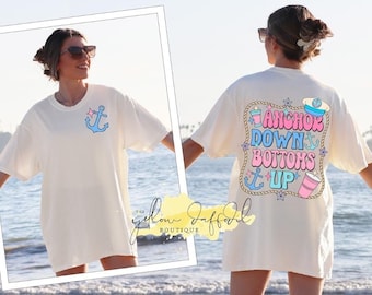 May include: White oversized t-shirt with a blue anchor and a pink star on the front. The back of the shirt has a graphic with the text "Anchor Down Bottoms Up" in pink, blue, and white with a blue anchor, a pink cup, and a blue captain's hat.